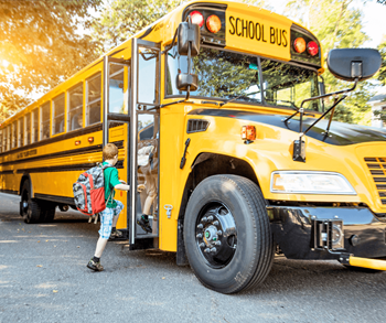 A child is getting off a yellow school bus.